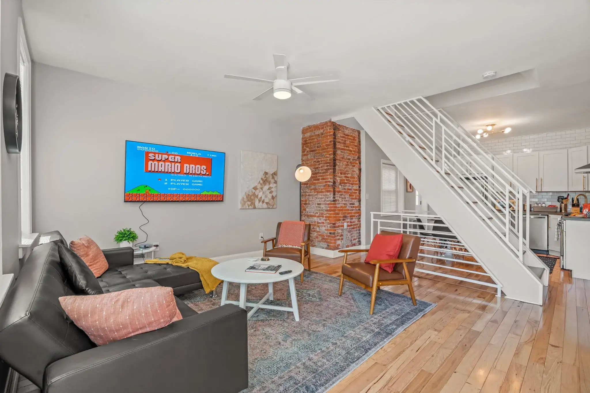 Relax in the cozy living room featuring exposed brick, sleek décor, and a large smart TV—plus retro Super Mario Bros. for fun nights in!