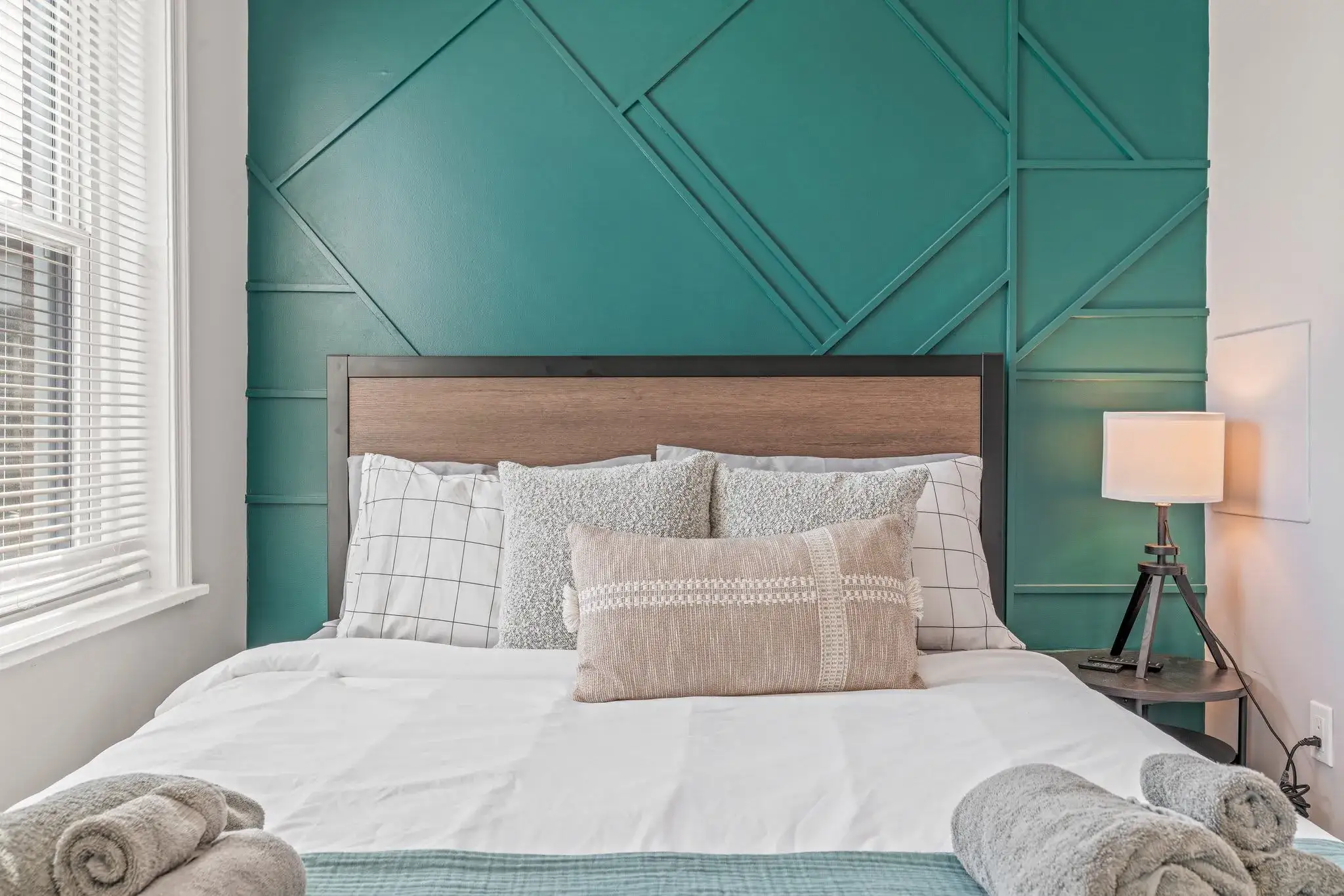 Inviting queen bed framed by a dramatic teal accent wall—designed for both style and comfort.