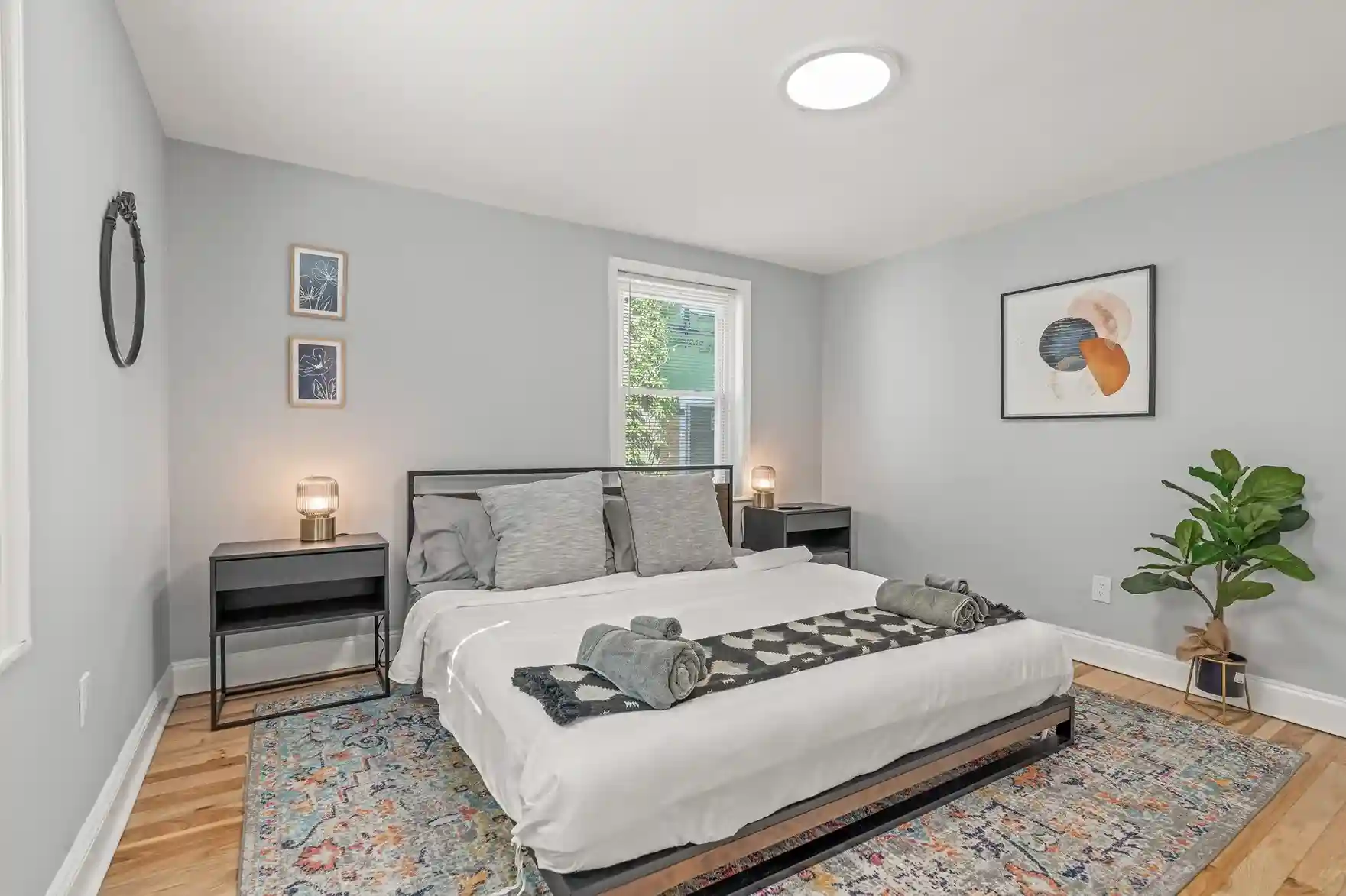 Spacious king bedroom with soft gray tones, modern art, and lush greenery—your private haven for restful nights.