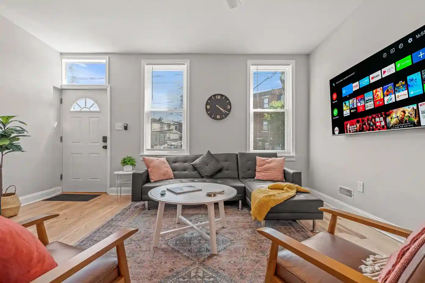 Stylish entry leads into a welcoming lounge with plenty of seating, warm accents, and a large smart TV for entertainment.