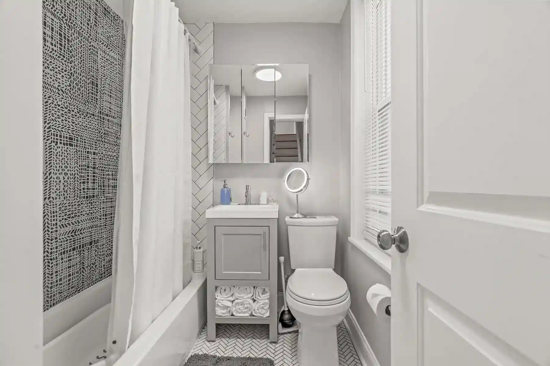 Freshly renovated bathroom with chic tilework, rain shower, and plush towels—bright, stylish, and spotless.