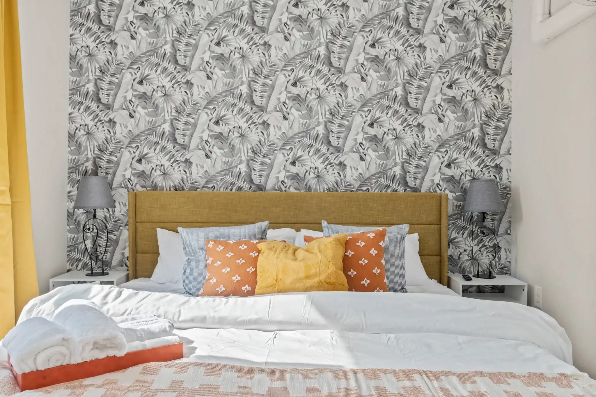 Cozy, colorful bedding and statement wallpaper create the perfect modern-meets-tropical hideaway.