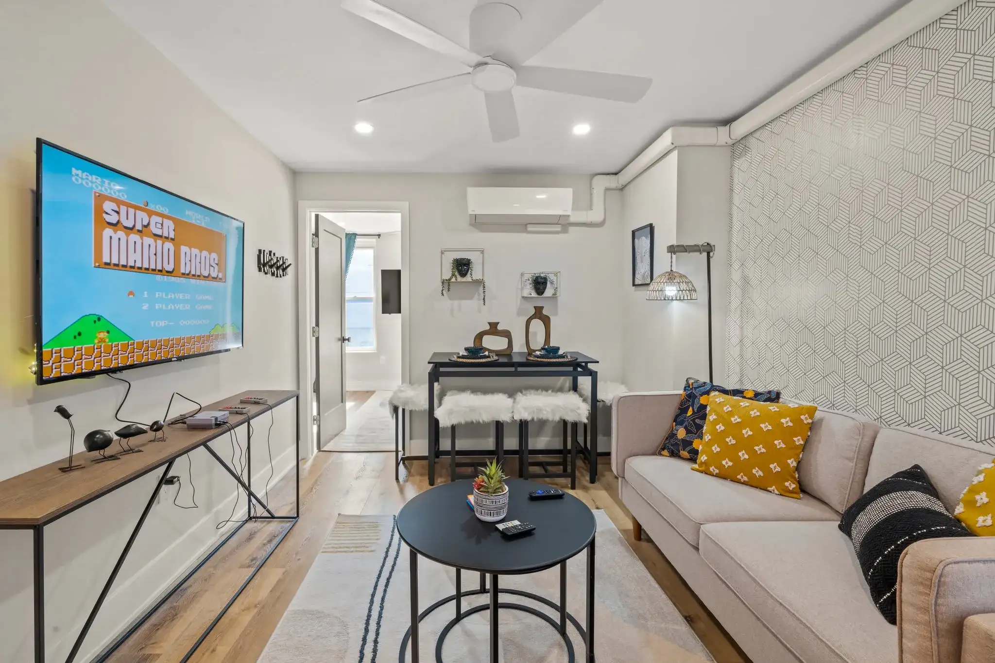 Bright, seamless flow from living to kitchen with warm wood floors and geometric wallpaper for modern Philly charm.