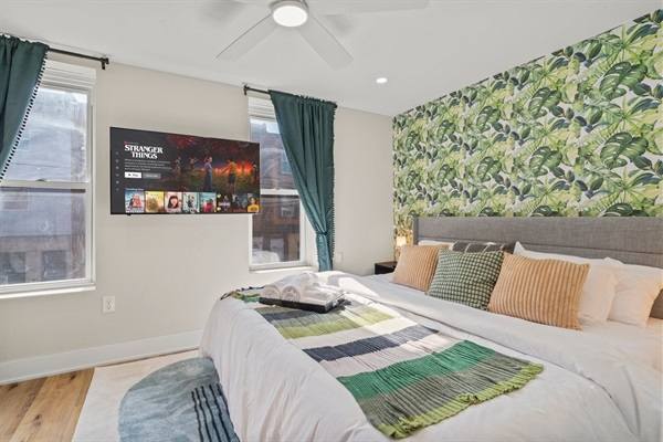 Tropical-inspired bedroom featuring a king bed, bold accent wall, and streaming TV for a peaceful night’s rest.