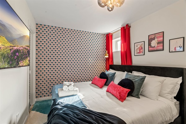 Relax in this stylish bedroom! With a large TV to enjoy your favorite shows, along with plush bedding and decorative pillows, it's designed for comfort. The welcoming atmosphere ensures a restful stay, making it the perfect retreat.