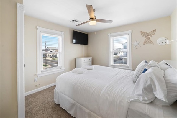 Bright windows and soft white bedding make this cheerful bedroom a fresh and cozy haven.