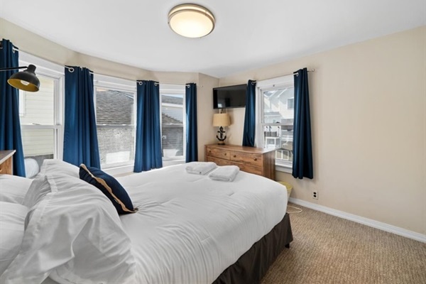 Wake up to sunlight streaming through bay windows in this elegant room with coastal navy accents and a smart TV.