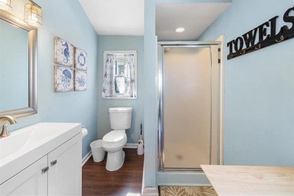 Bright bath with step-in shower and towel hooks—rinse, hang suits, and you’re ready for dinner on the island.