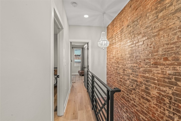 The exposed brick and chandelier add warmth and style as you move between cozy bedrooms upstairs.