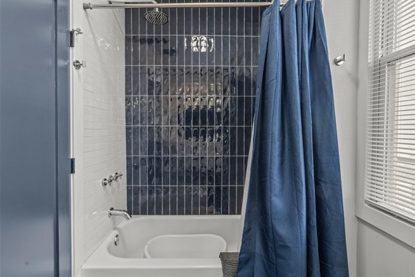 The deep blue tile and rainfall shower bring a modern, calming touch to your daily routine.