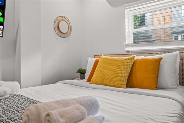 Appreciate the charming details of this serene bedroom. The cozy bed, vibrant pillows, and peaceful ambiance make it the ideal retreat for relaxation and comfort.