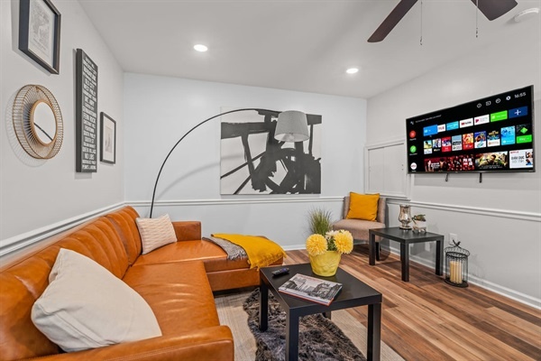You will love the cozy charm of this inviting living room! With its stylish decor, comfortable leather sofa, and vibrant accents, it's the perfect place to unwind and enjoy your favorite shows on the large flat-screen TV.