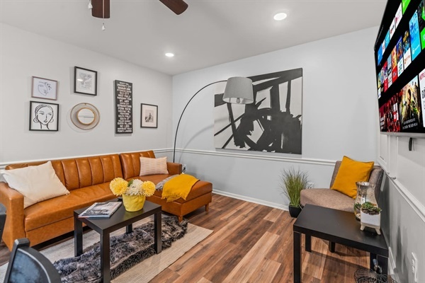 You will appreciate the stylish design of this living space! The sleek leather sofa, eclectic wall art, and vibrant accents create a welcoming ambiance that invites you to relax and unwind in comfort.