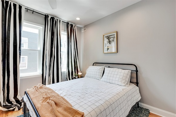 Step into this bright and modern bedroom—natural light, crisp linens, and bold drapery set the tone for a stylish, restful stay.