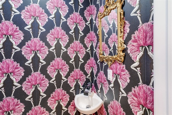 A playful touch—this vibrant powder room pairs bold wallpaper with a vintage gold mirror for true character.