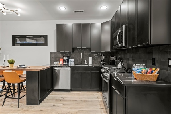 Cook, dine, and unwind — this modern kitchen with sleek black cabinetry and warm wood tones is made for connection.