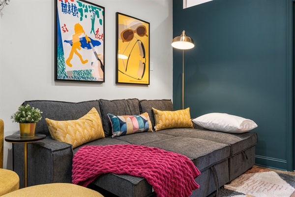 Kick back in style on your convertible sofa bed— bold art, soft textures, and vibrant accents make this lounge your happy place.