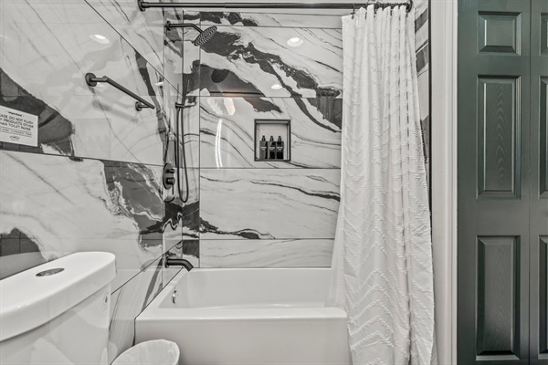 Enjoy a soothing soak or refreshing rinse surrounded by elegant marble tile and premium bath essentials.