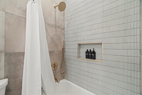 Enjoy a rainfall shower surrounded by modern tile and stocked essentials for a truly relaxing experience.