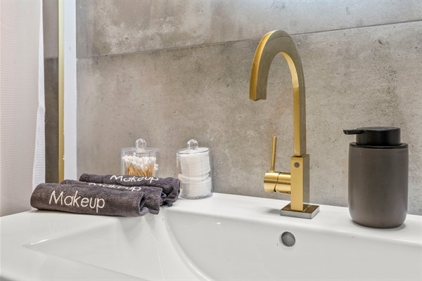 You will appreciate the elegant bathroom with its gold accents and contemporary design. The well-appointed vanity area includes everything you need for a luxurious experience.