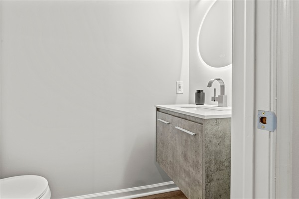 Appreciate the sleek design of this pristine half-bathroom. Its minimalist aesthetic, soft lighting, and modern fixtures create a tranquil space where you can refresh and relax during your sta