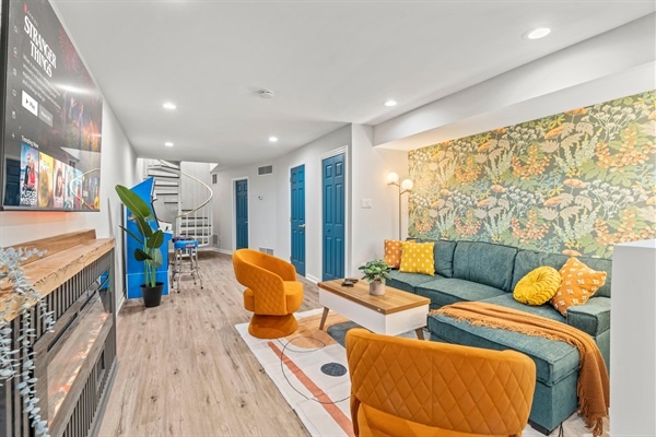 Immerse yourself in comfort and style in this chic living area with vibrant accents. You will love the cozy seating, inviting wallpaper, and modern entertainment setup, perfect for unwinding a