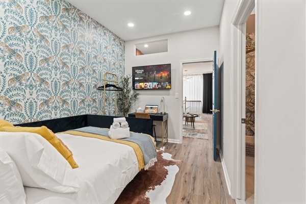 You will love the cozy bed with vibrant cushions and fresh linens. Enjoy the chic wallpaper, a convenient workspace with a TV, and thoughtful decor. The inviting atmosphere promises a restful