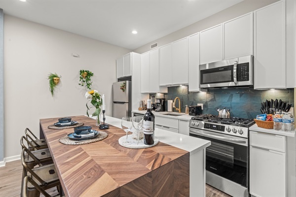 You'll love preparing meals in this modern kitchen, equipped with stainless steel appliances and ample counter space. Enjoy dining at the stylish wooden breakfast bar, perfect for sharing a glass of wine and delightful conversations.