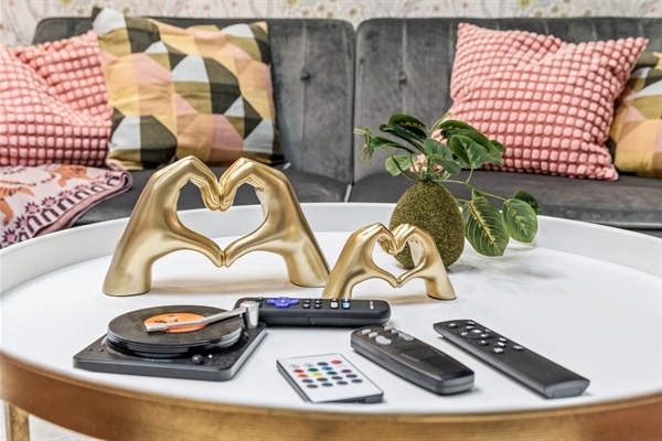 Admire the thoughtful details on the coffee table, featuring elegant decor and essential remotes for your entertainment needs. The charming heart sculptures add a touch of warmth and personality to the living space.