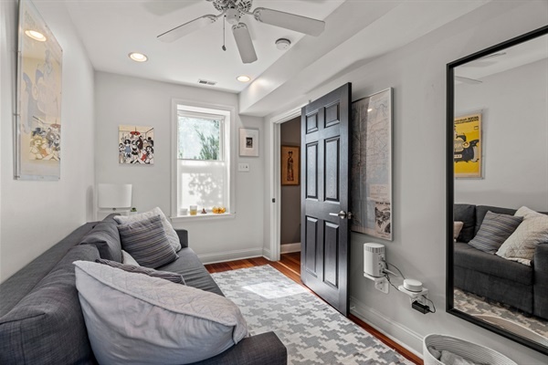 An overview of the cozy living room / 2nd bedroom with ample natural light, a ceiling fan, and modern decor.