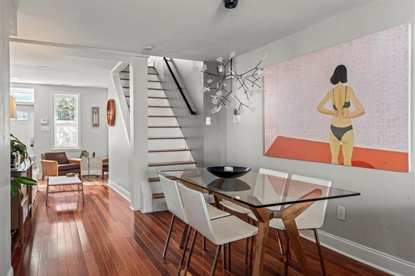 The dining area is stylish and modern, with a glass-top table and contemporary art.