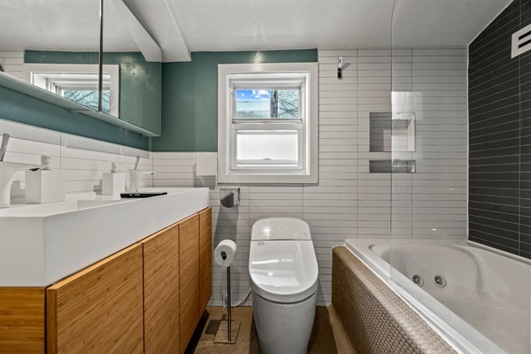 Indulge in luxury in this sleek, modern bathroom featuring a dual vanity and a soothing spa tub. You'll feel pampered with every amenity at your fingertips in this beautifully designed space.