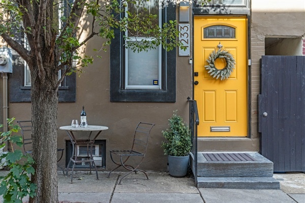 Enjoy a glass of wine at this delightful outdoor bistro set, right by the welcoming yellow door of your charming urban retreat. This cozy spot is perfect for morning coffee or evening relaxati