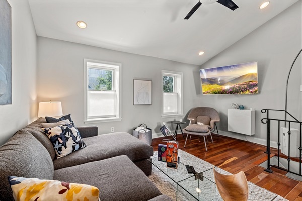 Enjoy cozy evenings in this chic living room with a comfortable sectional sofa, stylish decor, and a large TV, ideal for movie nights or casual lounging.