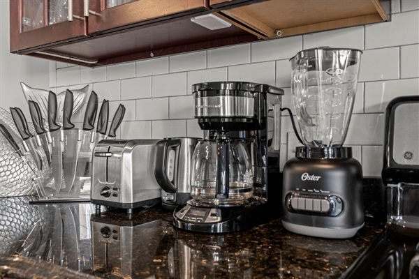 The kitchen is equipped with all essentials, including a coffee maker, blender, toaster, and knife set.