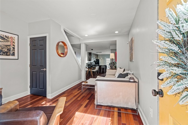 Step into this inviting living space, where sunlight dances on gleaming hardwood floors and modern decor welcomes you warmly, flowing effortlessly from the cozy seating area to the sleek dinin