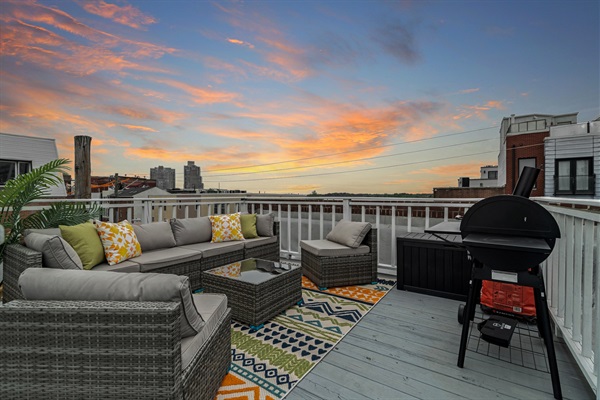 Golden hour on the roof deck — unwind in plush seating as the city glows beneath a brilliant Philadelphia sunset.