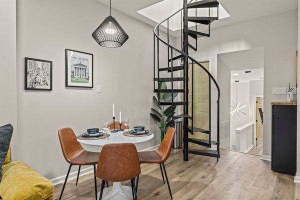 A cozy dining corner framed by modern lighting and a dramatic spiral staircase — perfect for memorable meals.