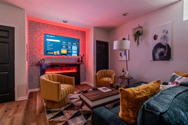 Settle in for movie night — ambient lighting, plush seating, and a glowing fireplace create the perfect vibe.