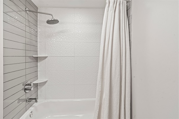 Crisp and sparkling clean shower-tub combo with designer tile and a rainfall showerhead for a relaxing rinse.