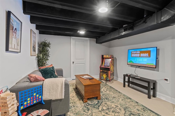 The entertainment room in the basement is a gamer’s paradise, featuring a retro arcade machine, board games, and a TV setup for endless fun and nostalgia.