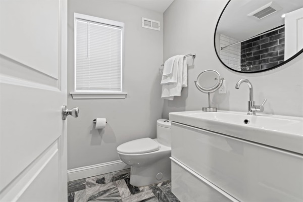 Enjoy the clean and modern bathroom, featuring chic decor and all the essentials for your comfort. The bright, inviting space is perfect for a refreshing start to your day.