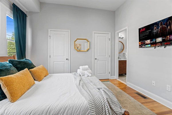 You will appreciate the stylish comfort of this bedroom, complete with a cozy bed, vibrant pillows, and a wall-mounted TV for your entertainment. Unwind and relax in this inviting space after a day of exploring!