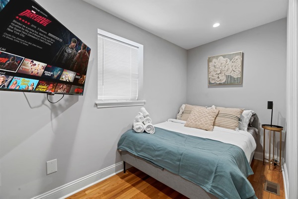Enjoy a peaceful retreat in this cozy bedroom, equipped with a comfortable bed, plush pillows, and a convenient wall-mounted TV. It's an ideal spot for relaxation and catching up on your favorite shows!