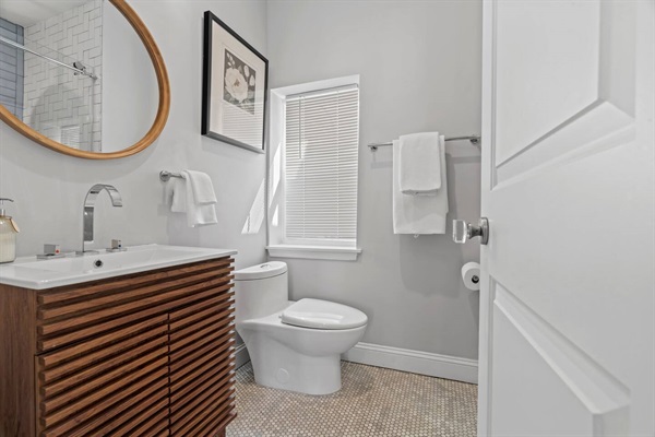 This modern bathroom offers a refreshing escape with its sleek design, large mirror, and well-lit vanity. You'll find everything you need to start or end your day feeling revitalized and pampered.