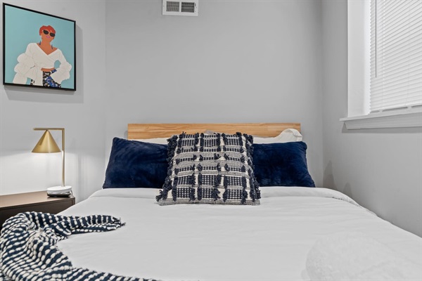 Enjoy the modern flair of this stylish bedroom. The chic decor and comfortable bed, paired with the unique artwork and sleek lighting, make for a perfect relaxing space during your stay.