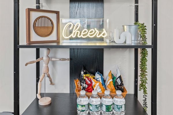 Enjoy a warm welcome—snacks, drinks, and a cheerful “cheers” bar shelf waiting to greet you.